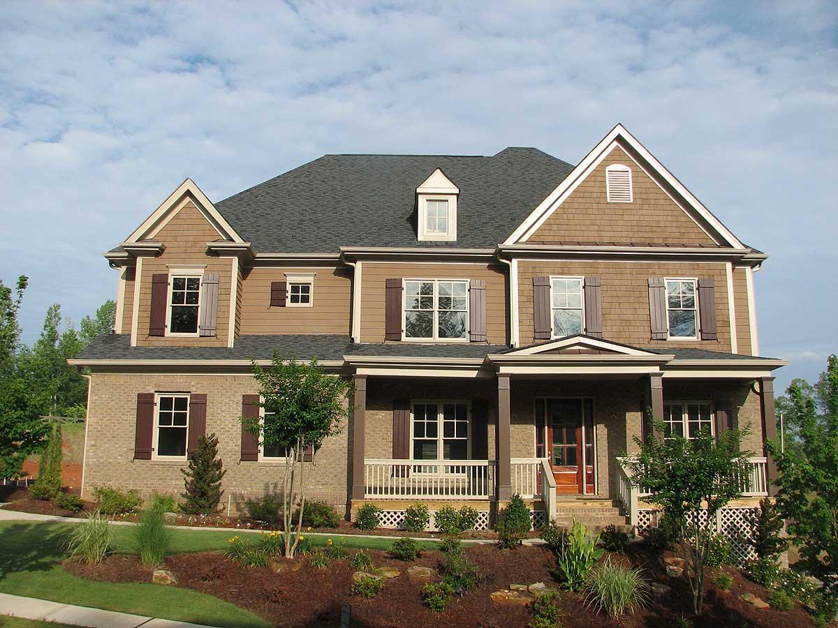 House plan exterior: Two-story home with gabled dormer, brick and shingle siding, and a covered front porch.