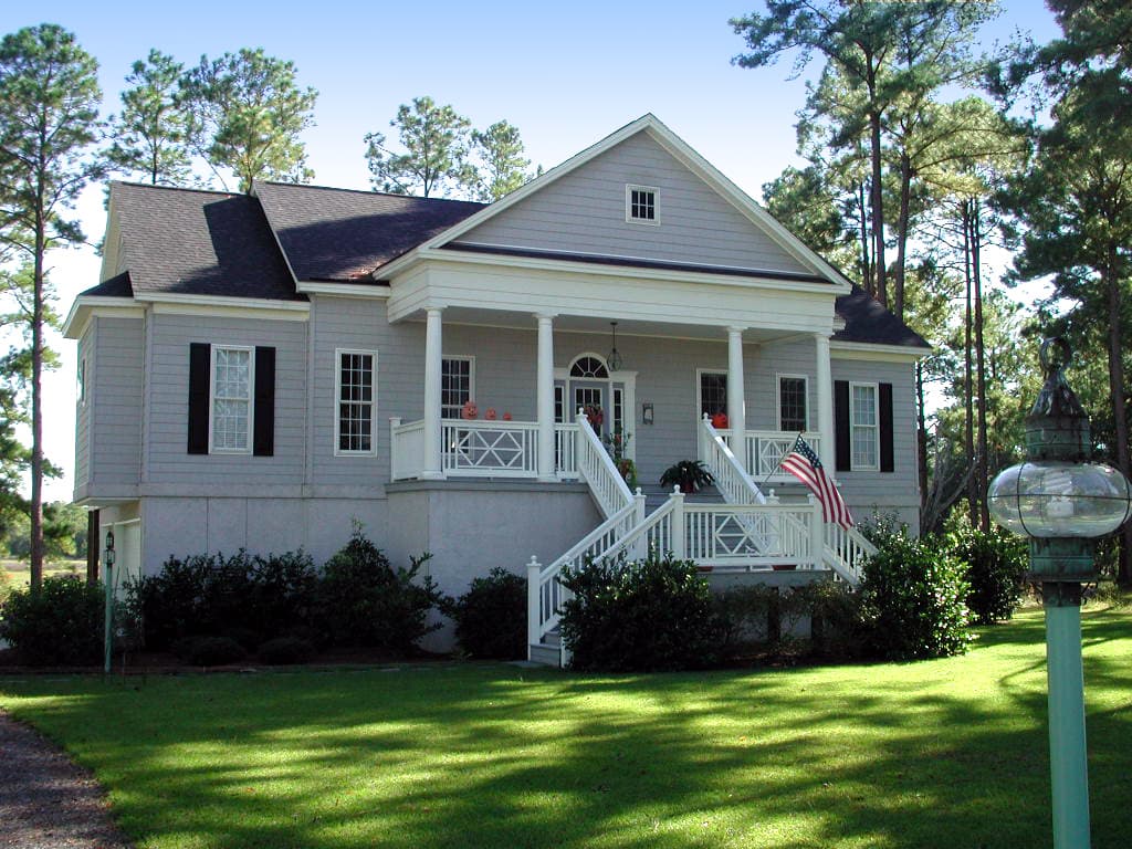 House plan exterior featuring a two-story house with a prominent covered front porch supported by columns, and a prominent central gable.