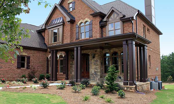 House plan exterior: Two-story brick home with covered porch, stone accents, arched windows, and multiple gables.