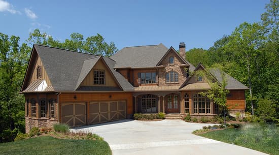 House plan exterior: Two-story home with stone and wood siding, multiple gables, a covered porch, and a three-car garage.