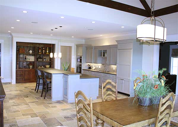Open concept kitchen with island, custom cabinetry, and dining area featuring a large wooden table and chairs.