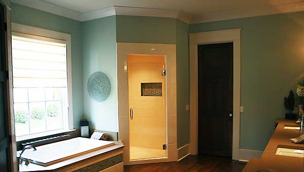 Bathroom interior with bathtub, glass-door shower enclosure, and dark wood door.