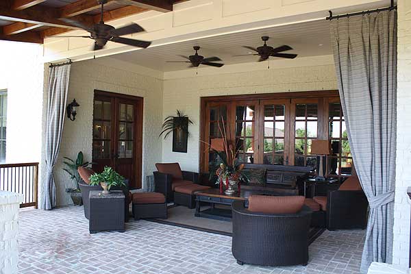 Covered patio with ceiling fans, large glass doors, and outdoor seating.