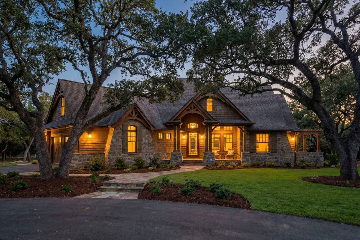 House plan exterior with Craftsman style, single story, stone and shake siding, front porch, and gabled rooflines. Includes a detached garage.