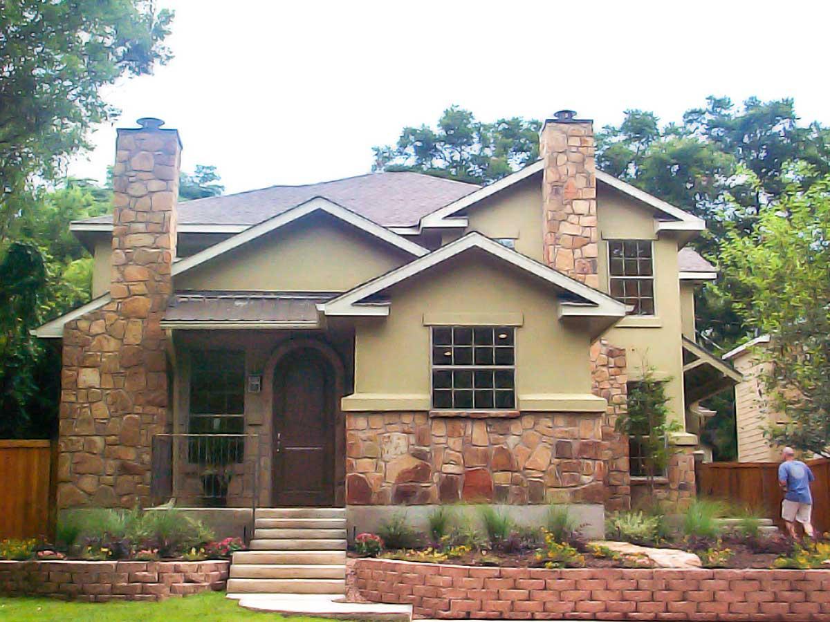 House plan exterior: Two-story home with stone chimneys, arched entry, gables, and multi-paned windows.