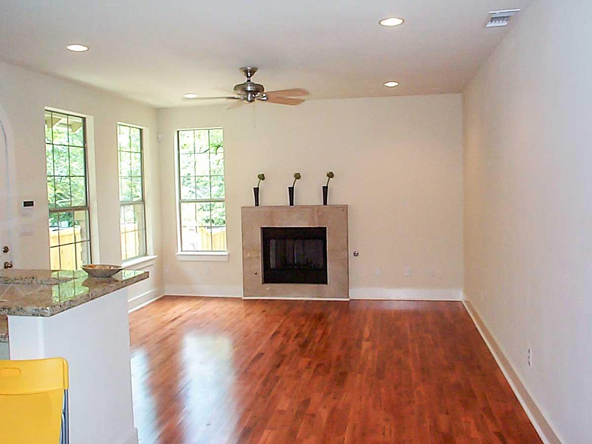 Interior view of a living room with a stone fireplace, ceiling fan, three windows, and a granite countertop.