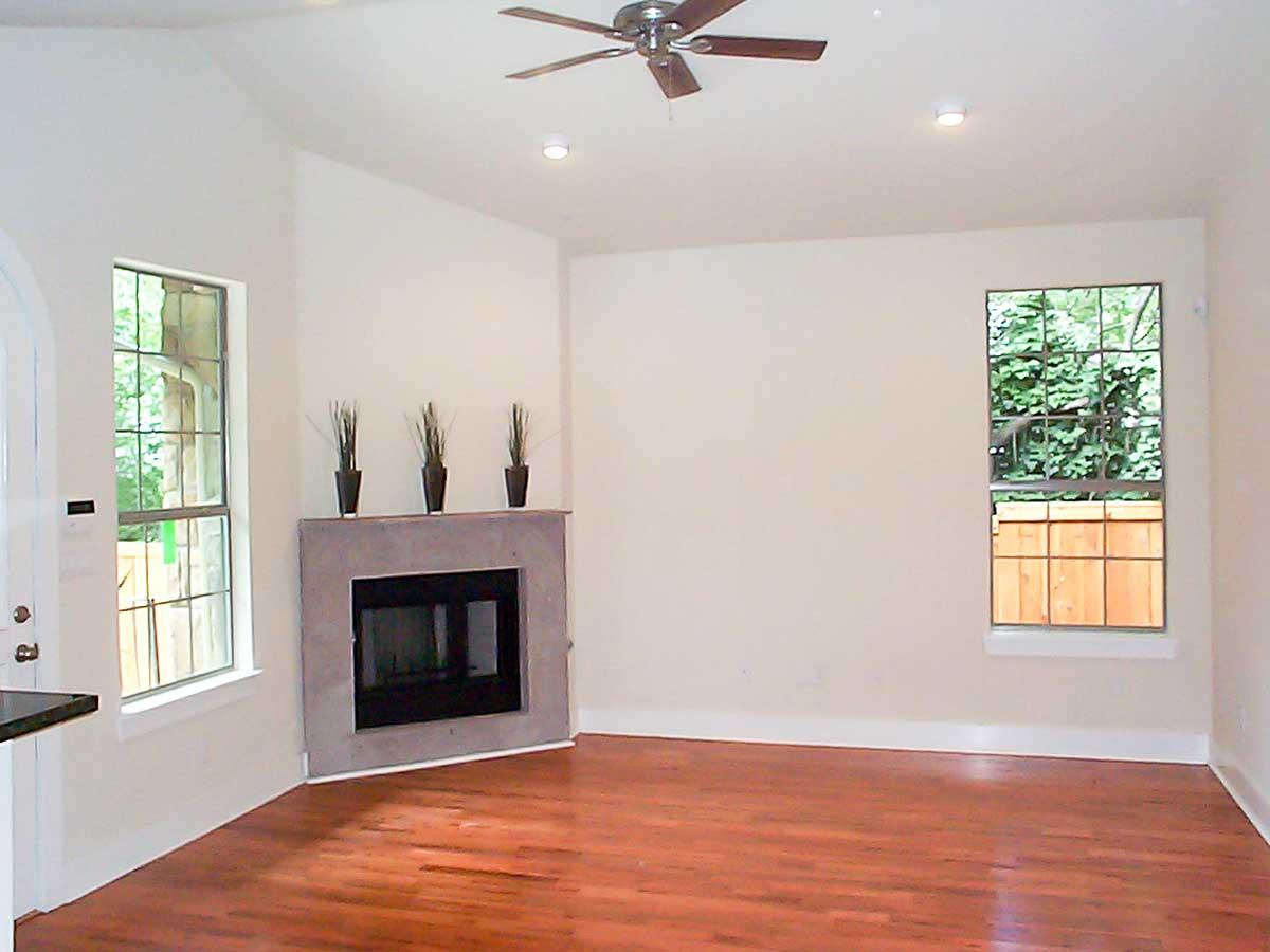 Interior view of living room with vaulted ceiling, fireplace, and multiple windows.