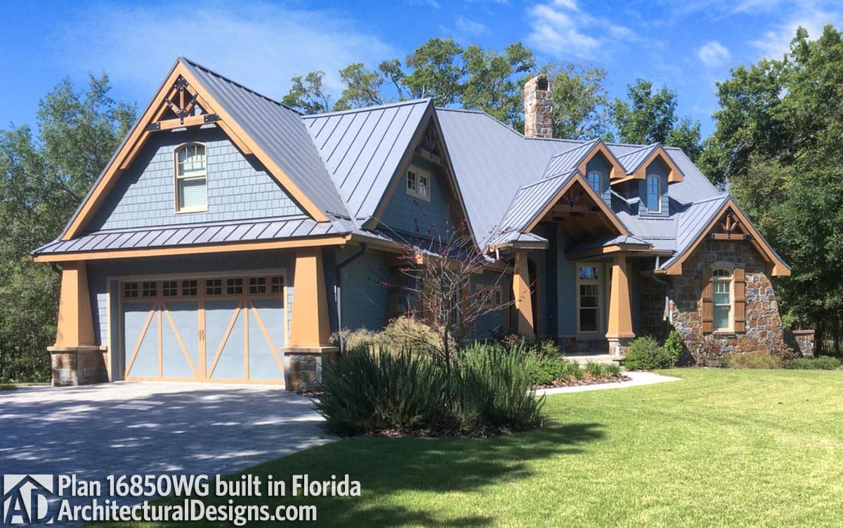 House plan exterior: Two-story Modern Farmhouse with metal roof, prominent gables, stone accents, and a three-car garage.