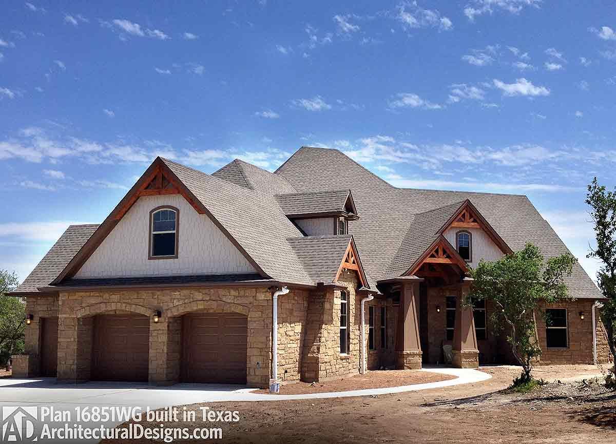 House plan exterior with stone facade, three-car garage, arched entry, and multiple gables.