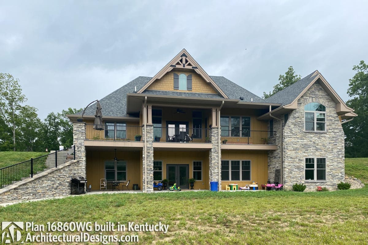 House plan exterior with stone accents, a covered balcony, gables, and multiple windows. Modern Farmhouse style.