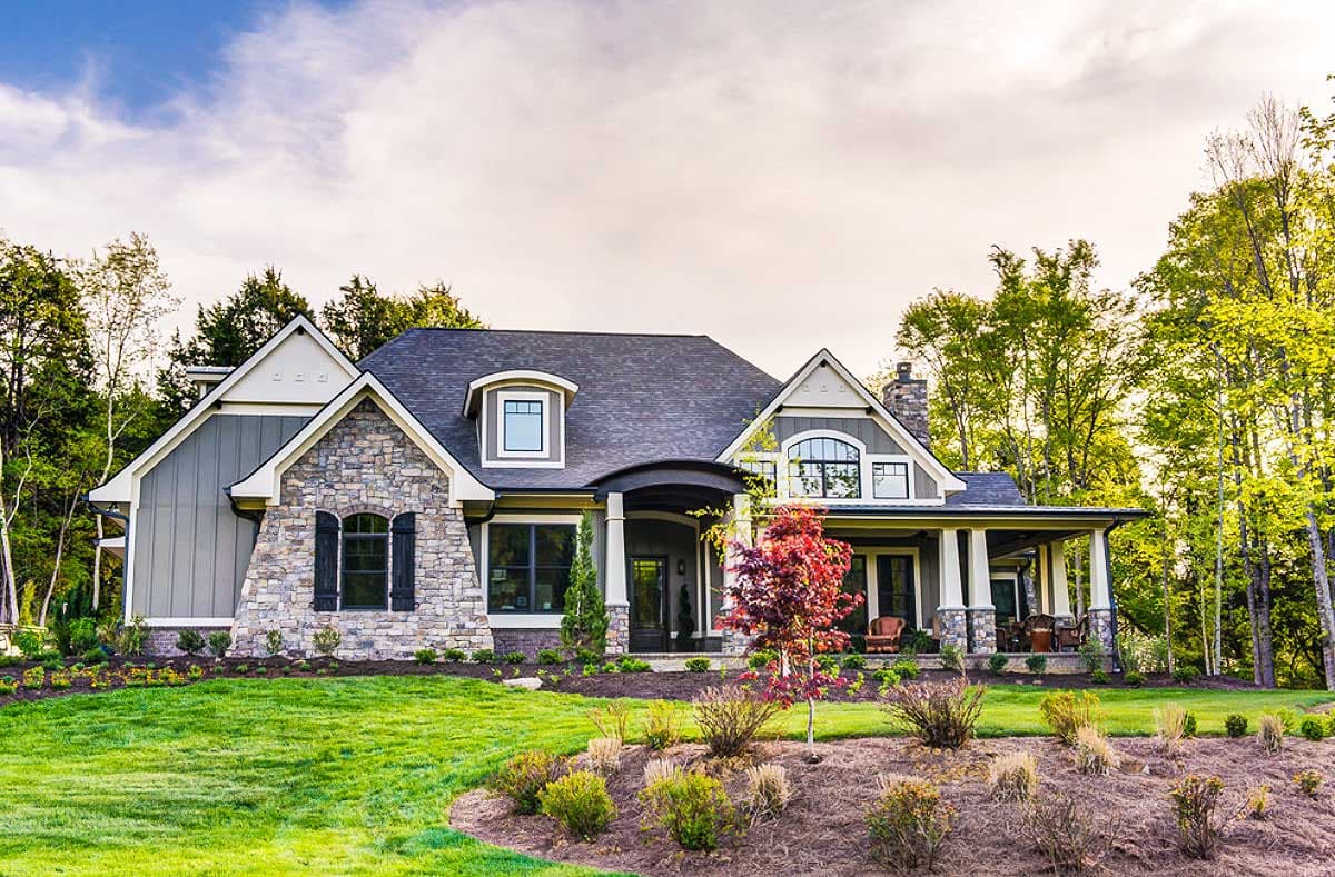House plan exterior. Craftsman style with stone facade and gabled roof. Features include dormers, a covered porch, and a chimney.