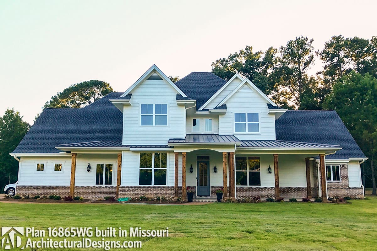 House plan exterior: Two-story modern farmhouse with a wraparound porch, gables, dormers, and prominent wooden columns.