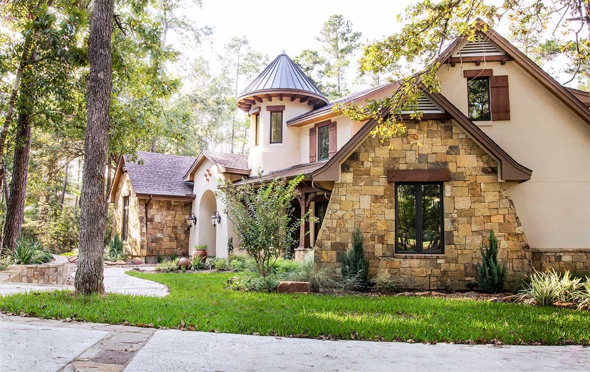 House plan exterior with stone facade, arched entry, and conical turret roof.
