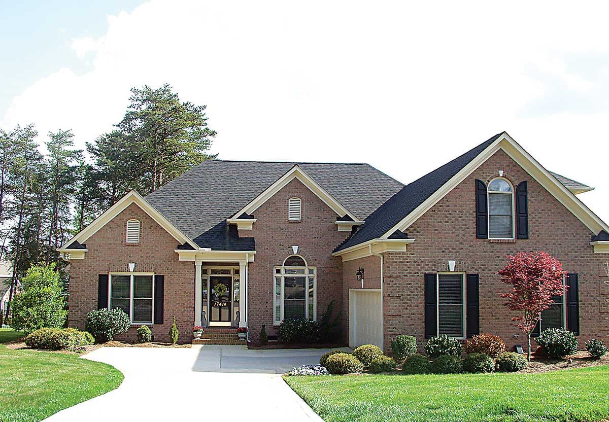 House plan exterior of a one-story brick home with a covered front entry, arched windows, multiple gables, and an attached garage.