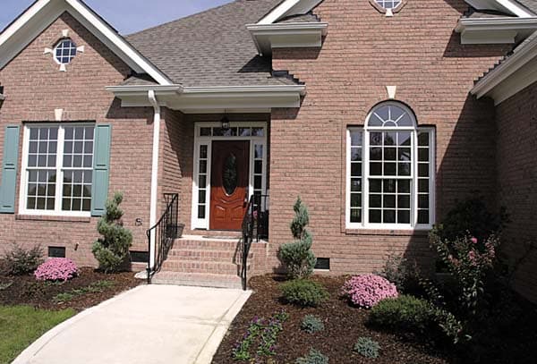 House plan exterior: Brick construction, arched top window, Palladian window, and covered entryway with a wood door.