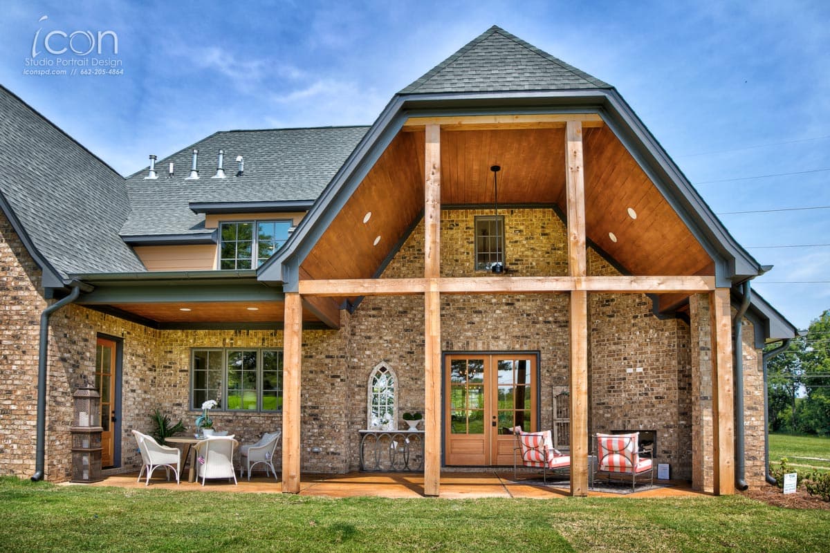 House plan exterior with brick facade, exposed wood beams, covered porch, and gabled roofline. Two stories visible.