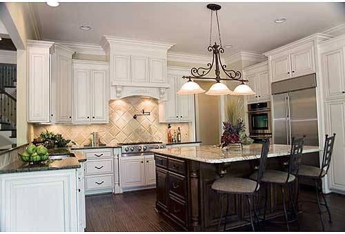 Kitchen with white cabinetry, granite island, stainless steel refrigerator, oven, and range.