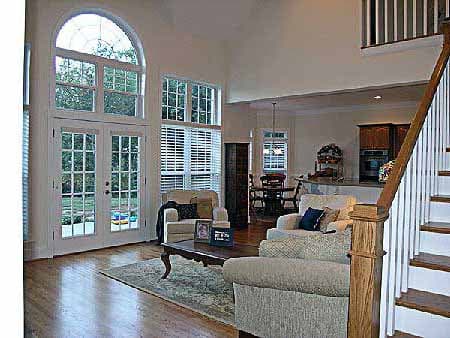Great room with two-story arched window, French doors, fireplace, and open staircase to second floor.