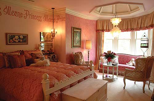 Bedroom interior with large bed, pink sofa, and bay windows. Octagonal ceiling detail above chandelier.