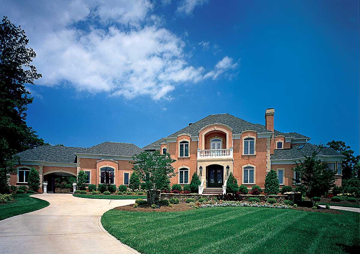 Exterior house plan with multiple gables, arched windows, a balcony, and a porte-cochere.