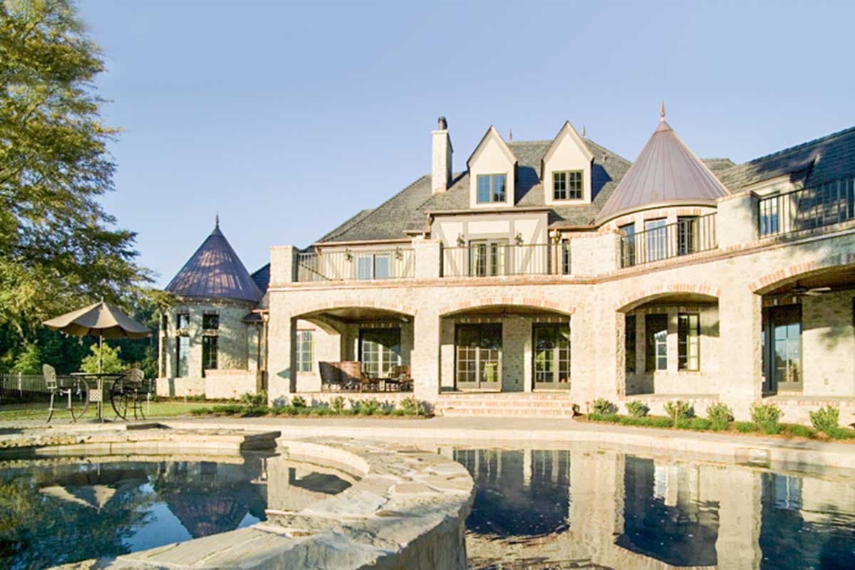 European-inspired house plan exterior with arched loggias, turrets, dormers, and a balcony.