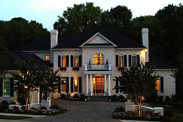 House plan exterior of a two-story home with a pitched roof, central gable, balcony, and shutters.