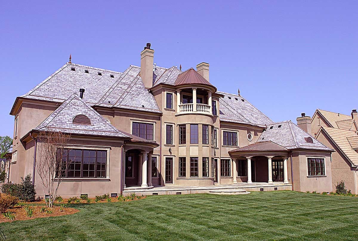 House plan exterior featuring a multi-story design with slate roofing, a circular balcony, multiple gables, and a covered portico.