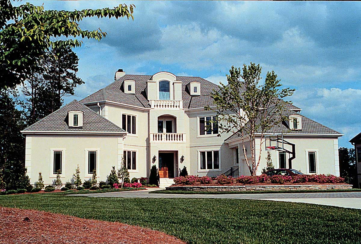 House plan exterior: Two-story home with hip roof, dormers, arched central balcony, and attached garage.