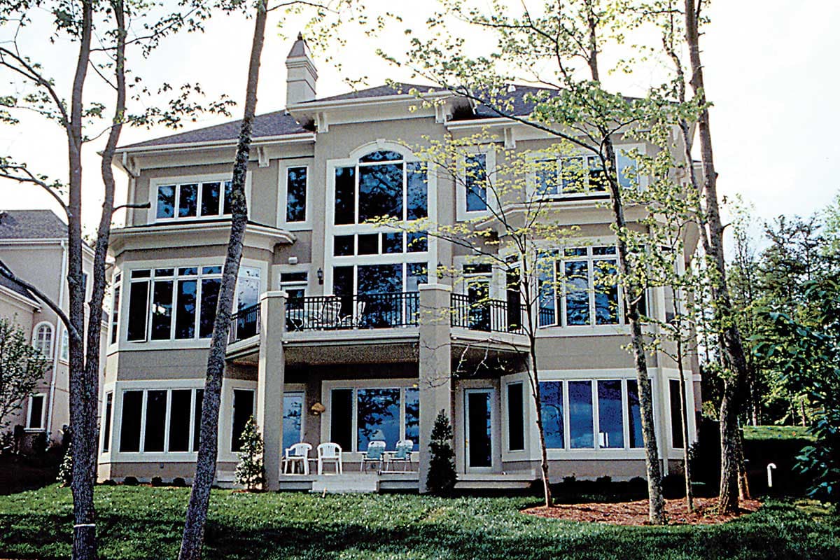 House plan exterior, contemporary style, three stories, featuring a balcony, large windows, and a prominent chimney.