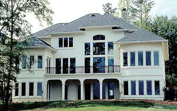 House plan exterior: two-story residence with arched entry, multiple gables, and a rear balcony overlooking a covered patio.