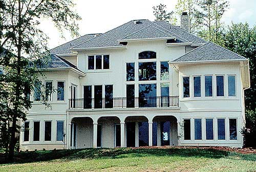 House plan exterior: Modern style, two stories, with multiple large windows, a second-story balcony, and a covered ground-level patio.
