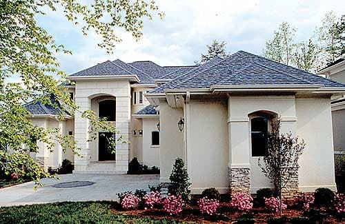 House plan exterior: European style, stucco finish, multiple gables, arched entryway with stone accents, and a two-car garage.