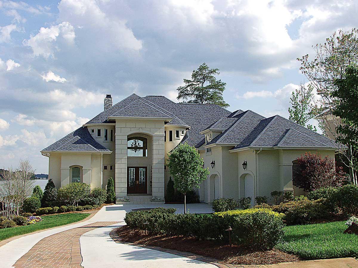 House plan exterior featuring a two-story, stone-accented facade, arched entry, dual garage doors, and multiple gabled rooflines.