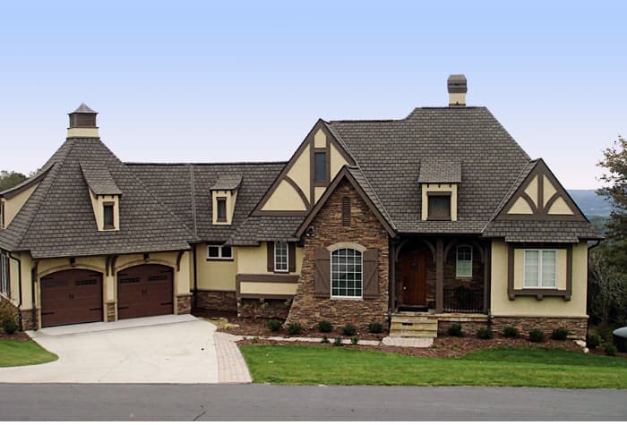 House plan exterior: French Country style, two stories, stone accents, multiple gables, and a three-car garage.