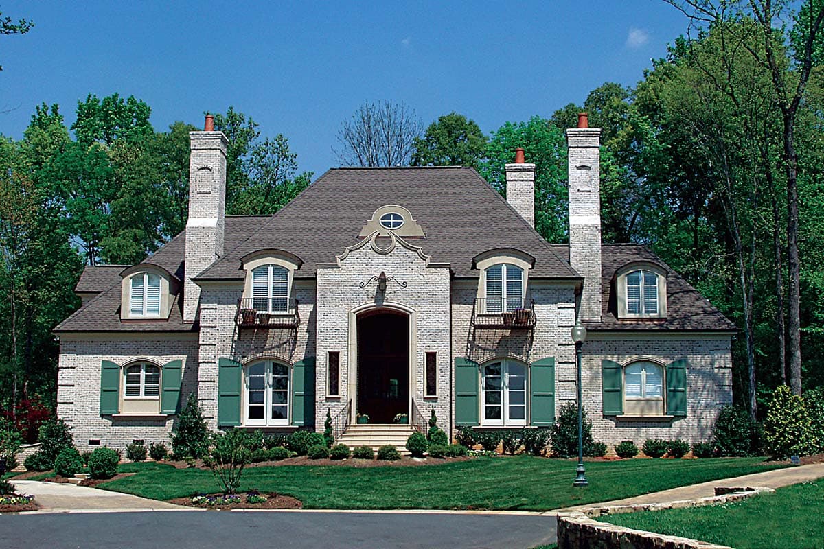 French Provincial house plan exterior with white brick, arched dormers, balconies, and symmetrical gables.