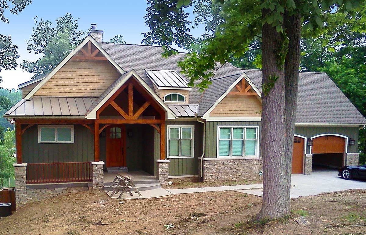 House plan exterior: Craftsman style, 1.5 stories, covered entry porch with exposed beams, dormer, and attached two-car garage.