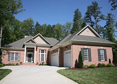 House plan exterior: Traditional brick ranch with a prominent gable, covered entry, and three-car garage.