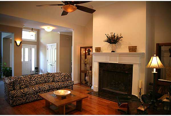 Great room with vaulted ceiling, fireplace, zebra print sofa, and entry foyer with double doors.