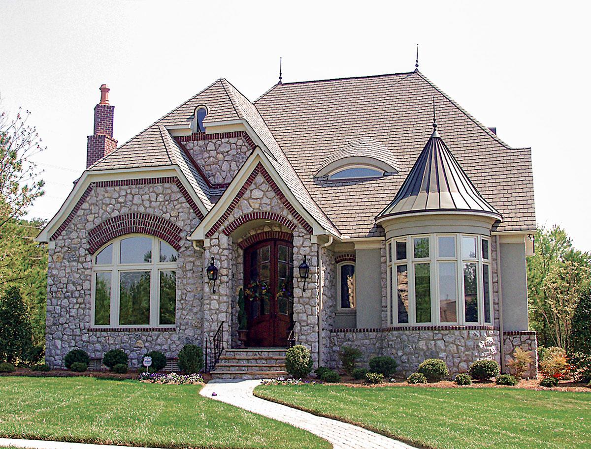 House plan exterior: Stone and brick facade, arched entry, dormers, turrets, and multi-level rooflines.