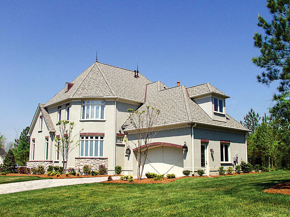House plan exterior: Two-story home with multi-level rooflines, prominent gables, and arched garage entrance.