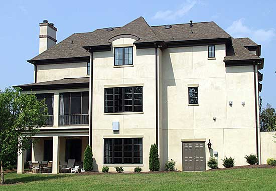House plan exterior: Two-story stucco home with a screened porch, large windows, gabled roof, and double garage door.