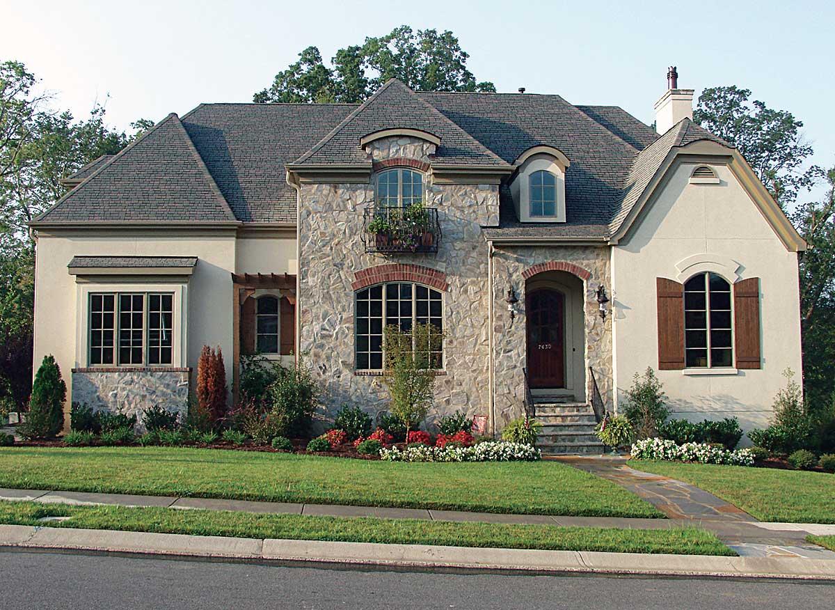House plan exterior: Stone and stucco two-story with arched dormers, prominent gables, and a covered entryway.