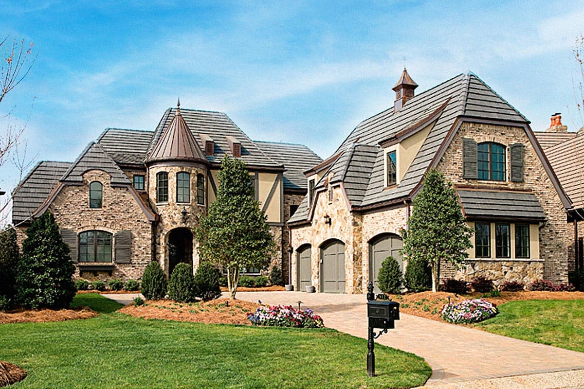 House plan exterior featuring stone and stucco, a prominent turret, multiple gables, and a three-car garage.
