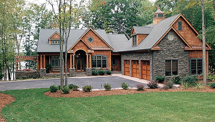 House plan exterior: Two-story Craftsman style with stone and wood shingle siding, arched entry, and three-car garage.
