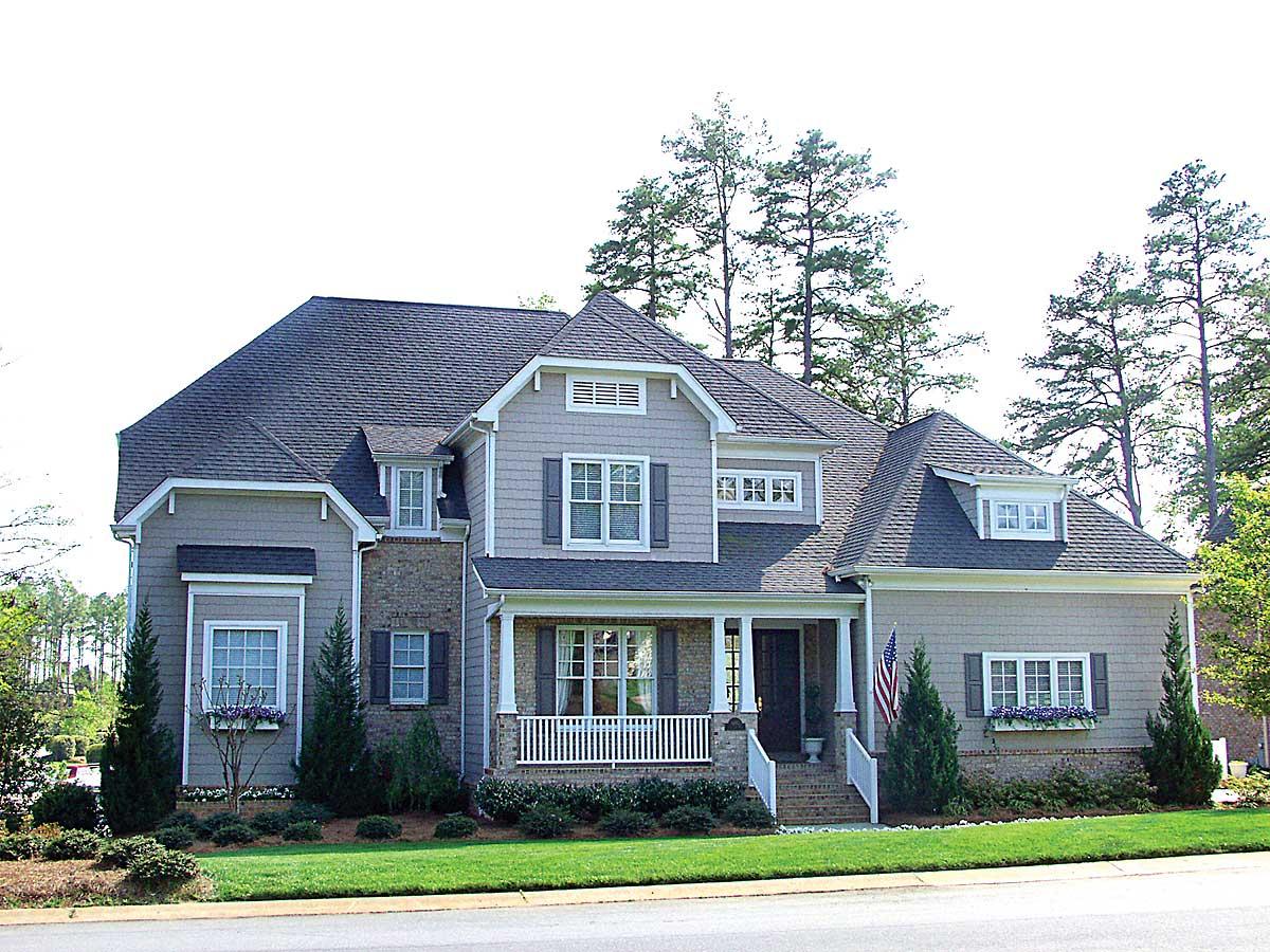 Two-story house plan exterior with a gabled roof, covered porch with white railings, and dormer windows.