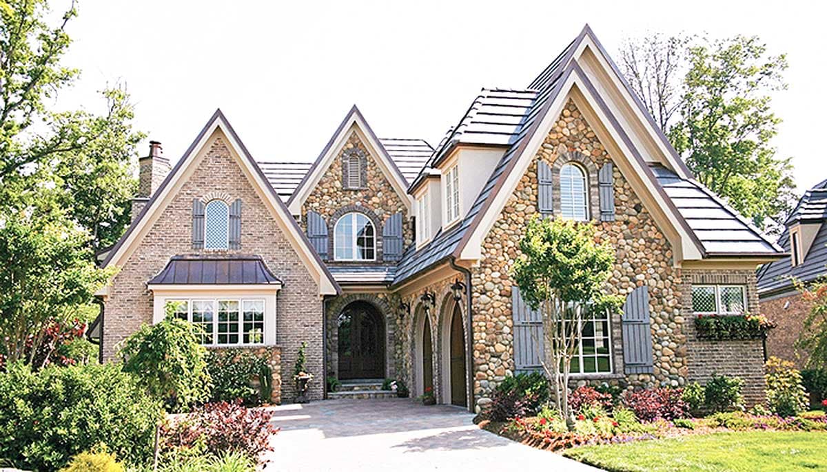 House plan exterior. Two-story, stone and brick facade, multiple gables, arched entry, and various window styles.