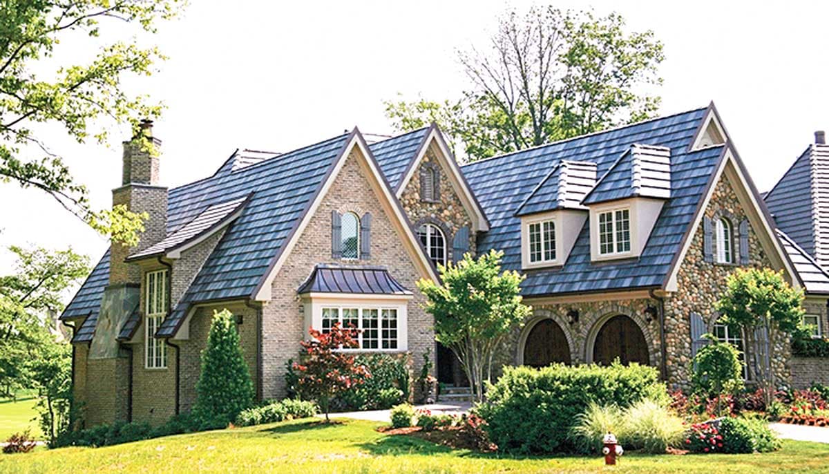 House plan exterior with stone and brick facade, steeply pitched rooflines, dormers, and arched entryway.