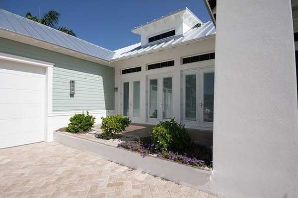 House plan exterior featuring metal roof, double garage door, and french doors with clerestory windows.
