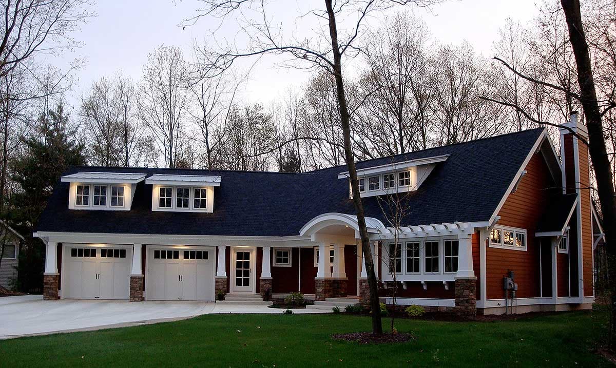 House plan exterior: Ranch style with three-car garage, dormers, arched entryway, and gabled roof.