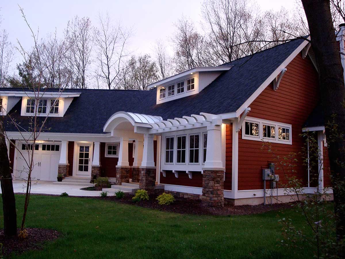 House plan exterior: One-story modern farmhouse with attached garage, arched entry pergola, dormer windows, and cedar shingle siding.
